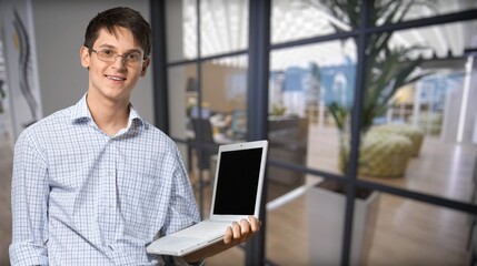 Portrait of a doubtful man holding laptop computer on background
