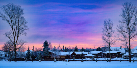Landscape with the image of winter russian village at sunset