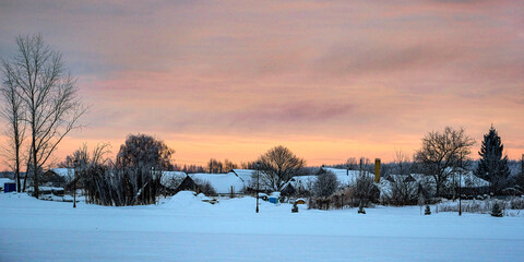Landscape with the image of winter russian village at sunset