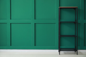 Empty modern shelf unit near green wall in room