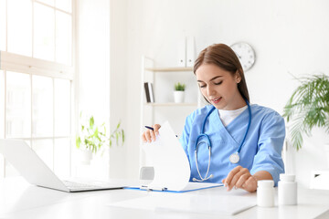 Female doctor working with clipboard at table in clinic