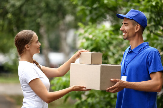 Young woman receiving parcels from courier outdoors