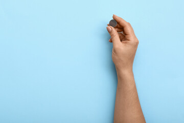Woman holding lithium button cell battery on blue background