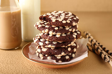 Plate of tasty cookies with white chocolate chips on beige background