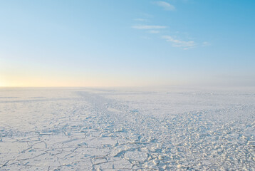 Baltic sea frozen ice cover to the horizon in winter sunrise