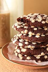 Plate of tasty cookies with white chocolate chips on beige background