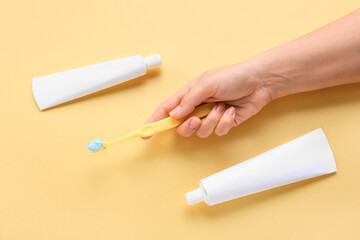 Female hand with tooth brush and paste on beige background