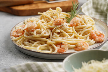 Flat plate with pasta spaghetti with heavy cream and roasted shrimps with garlic sauce and parmesan cheese on grey concrete surface