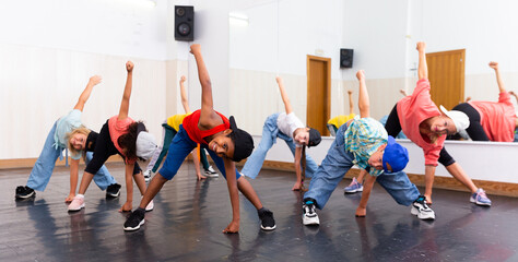 Cheerful preteen girls and boys hip hop dancers doing dance workout with female trainer during group class