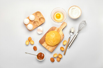 Wooden board of fresh dough for preparing walnut shaped cookies with boiled condensed milk and ingredients on light background