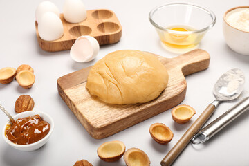 Wooden board of fresh dough for preparing walnut shaped cookies with boiled condensed milk and ingredients on light background