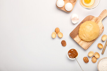 Wooden board of fresh dough for preparing walnut shaped cookies with boiled condensed milk and ingredients on light background