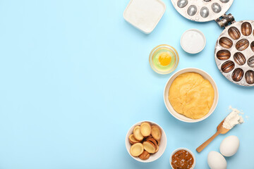 Bowl of fresh dough for preparing walnut shaped cookies with boiled condensed milk and ingredients on blue background