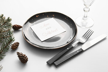 Beautiful table setting with wedding invitation and fir branches on light background