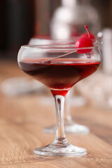 Glass of tasty Manhattan cocktail on wooden table, closeup