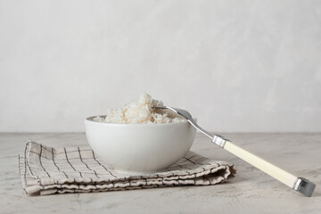 Bowl with tasty boiled rice on light background