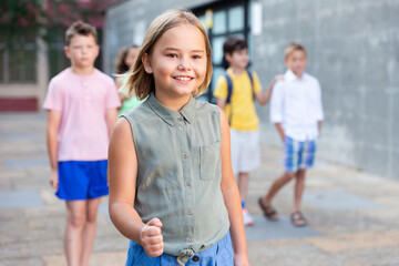 European preteen schoolgirl eight years old posing after lessons on street near school outdoors
