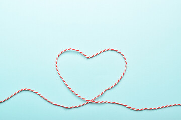 A painted heart with a red and white thread of love on a blue background. Background for Valentine's Day. Love inscription in red with space for text. Love inscription in red with space for text