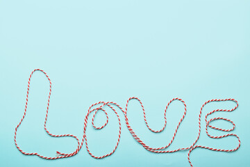 Inscription about love inscription in red and white threads about love on a blue background. Background for Valentine's Day. Love inscription in red with a space for the text