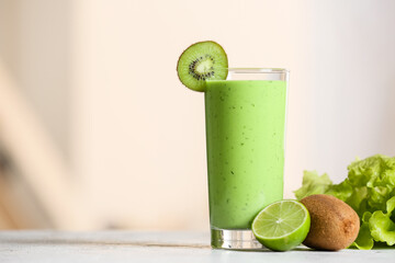 Glass of healthy green juice and fresh fruits on table against blurred background