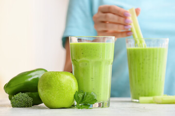 Glasses of healthy green juice and fresh ingredients on table against blurred background