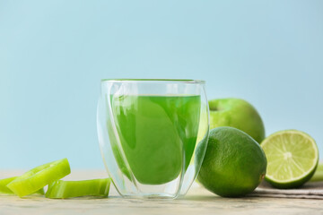 Glass of healthy green juice and fresh fruits on table
