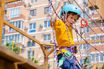 Obraz na płótnie Canvas boy crossing course high ropes element in adventure park outdoor. Concept Climbing extreme sport, physical development