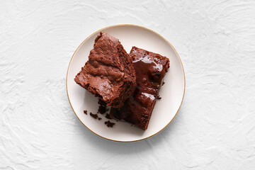 Plate with pieces of tasty chocolate brownie on white background