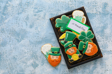 Board with tasty gingerbread cookies for St. Patrick's Day celebration on color background