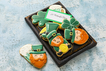 Board with tasty gingerbread cookies for St. Patrick's Day celebration on color background