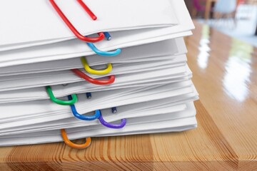 Pile of paperwork with colorful paper clips on office desk.  Administration of company's report...