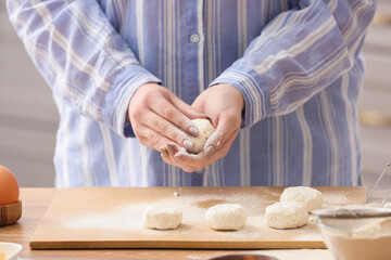 Woman preparing tasty cottage cheese pancakes at kitchen table, closeup