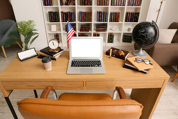 Laptop with blank screen and USA flag on desk in office