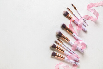 Set of makeup brushes with ribbon on light background
