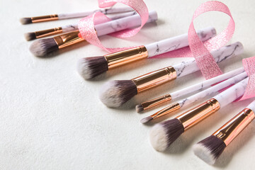 Set of makeup brushes with ribbon on light background, closeup