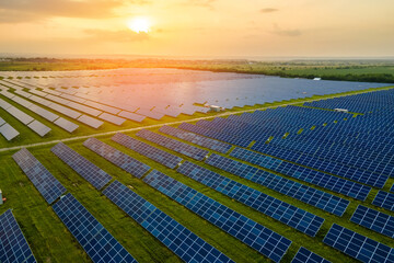 Aerial view of large sustainable electrical power plant with many rows of solar photovoltaic panels for producing clean electric energy in evening. Renewable electricity with zero emission concept