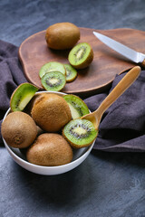 Bowl with fresh ripe kiwi on dark background, closeup