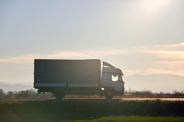 Cargo truck driving on highway hauling goods in evening. Delivery transportation and logistics...