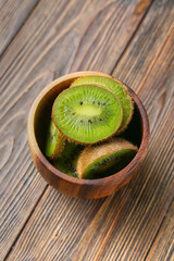 Bowl with fresh cut kiwi on wooden background