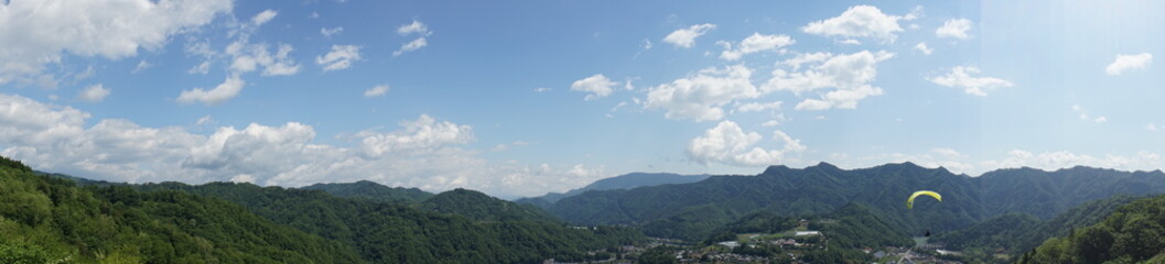 Fototapeta na wymiar 生坂村の里山とパラグライダー（パノラマ）
