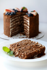 Piece of multi-layered honey cake with fresh berries. Selective focus.