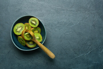 Bowl with fresh cut kiwi on black background