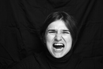 Young woman screaming, hate, rage. Crying emotional angry woman screaming on black background....