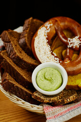 Bavarian bread basket with white, black bread, pretzel and sauce