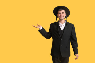 Hasidic Jewish man showing something on color background