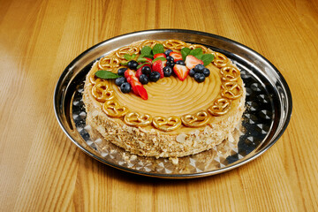 caramel cake with strawberries, blueberries and small pretzels