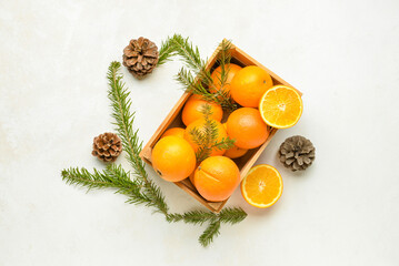 Wooden box with fresh oranges and fir branches on white background