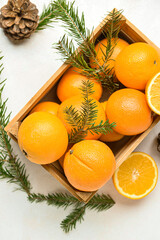 Wooden box with fresh oranges and fir branches on white background