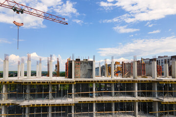 Tower crane at high concrete residential building under construction. Real estate development...