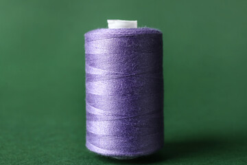 Purple sewing thread spool on color background
